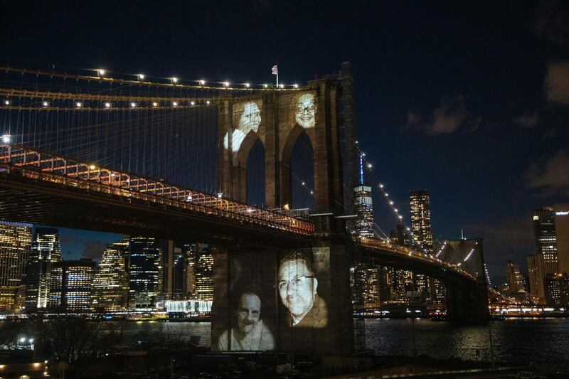 New Yorkers who died during the coronavirus pandemic are projected onto the Brooklyn Bridge during a commemoration ceremony Sunday, March 14, 2021, in Brooklyn, NY. (AP Photo/Kevin Hagen).