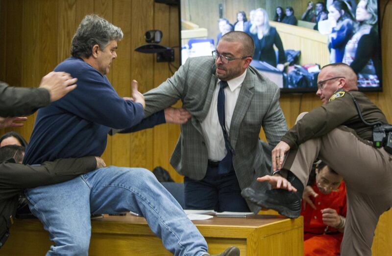 Randall Margraves, father of three victims of Larry Nassar , left, lunges at Nassar, bottom right, Friday, Feb. 2, 2018, in Eaton County Circuit Court in Charlotte, Mich.  The incident came during the third and final sentencing hearing for Nassar on sexual abuse charges. The charges in this case focus on his work with Twistars, an elite Michigan gymnastics club.   (Cory Morse/The Grand Rapids Press via AP)