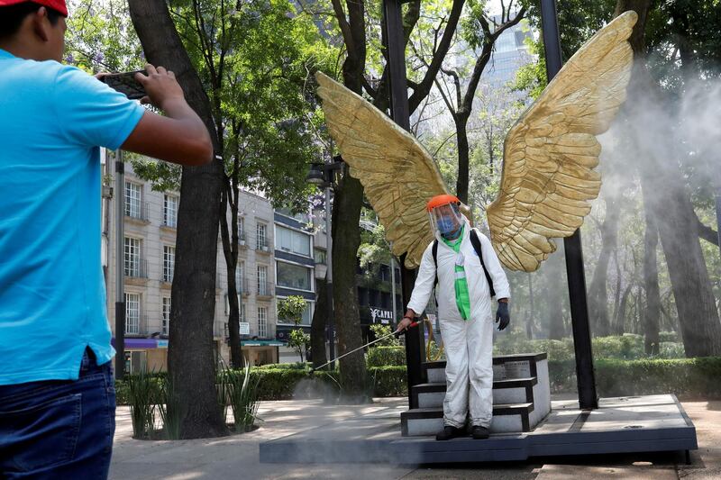A city employee, wearing protective gear, poses for a photograph as he disinfects an area of Paseo de la Reforma avenue as the coronavirus disease  continues in Mexico City, Mexico. Reuters