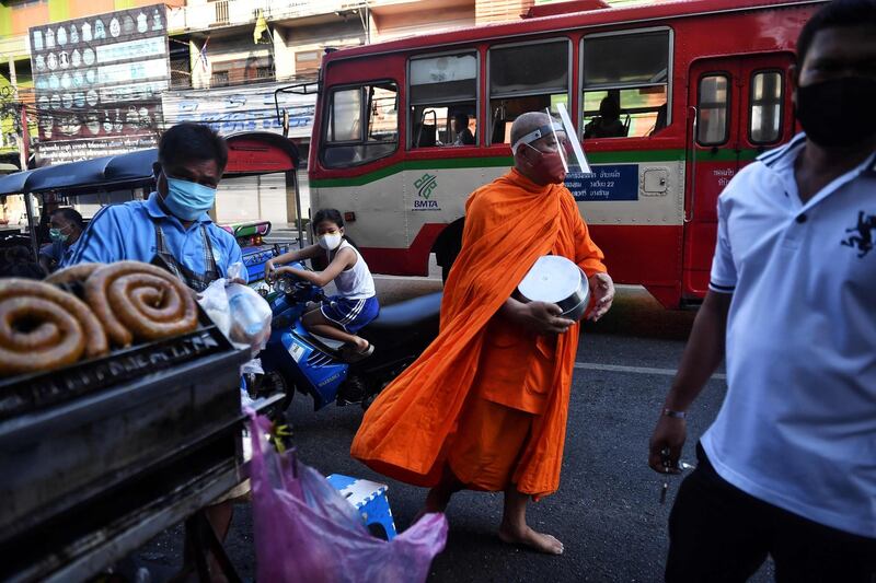 A Buddhist monk collects alms at an outdoor market in Bangkok, Thailand. AFP