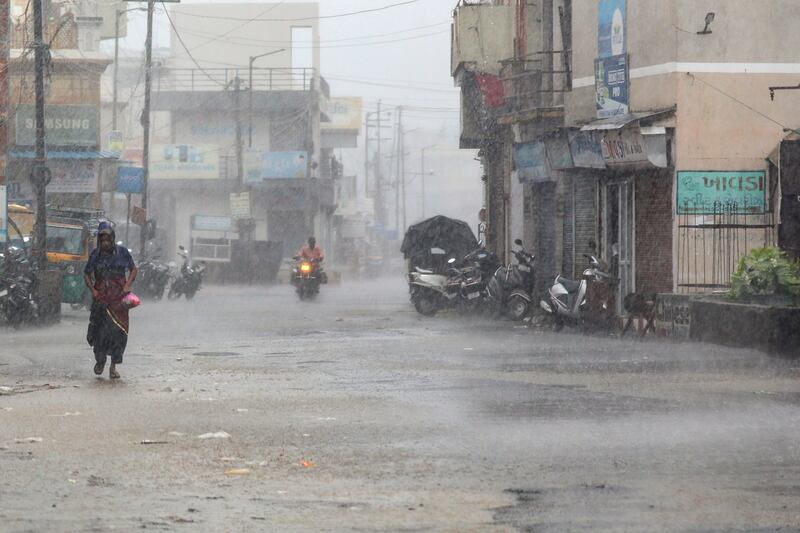 A person walks down a street during heavy rain in Mandvi. EPA
