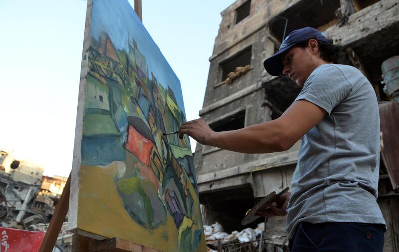 An artist paints, in the Yarmuk Palestinian refugee camp, on the southern outskirts of the Syrian capital, Damascus. AFP