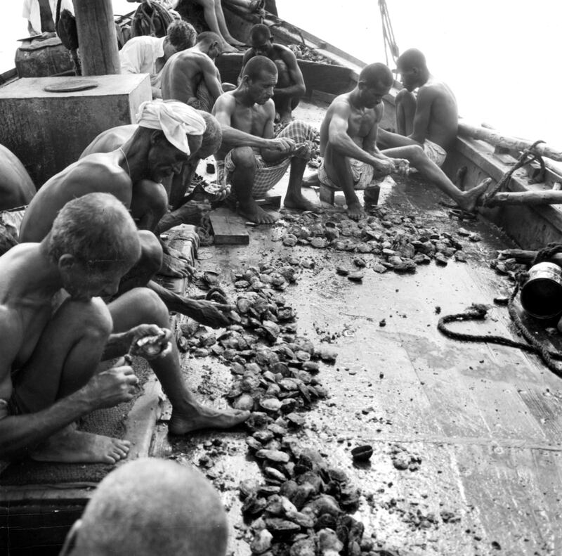 Pearl divers shell oysters for pearls on the deck of a boat in Bahrain, Persian Gulf, 1955. (Photo by Authenticated News/Archive Photos/Getty Images)