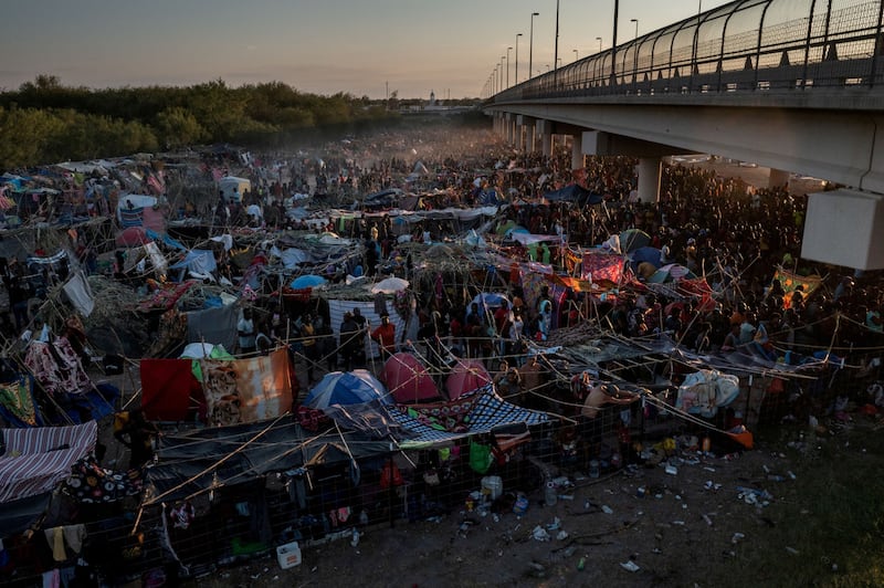 Migrants take shelter along the Del Rio International Bridge at sunset on September 19 as they wait to be processed after crossing the Rio Grande into the US from Mexico. Reuters