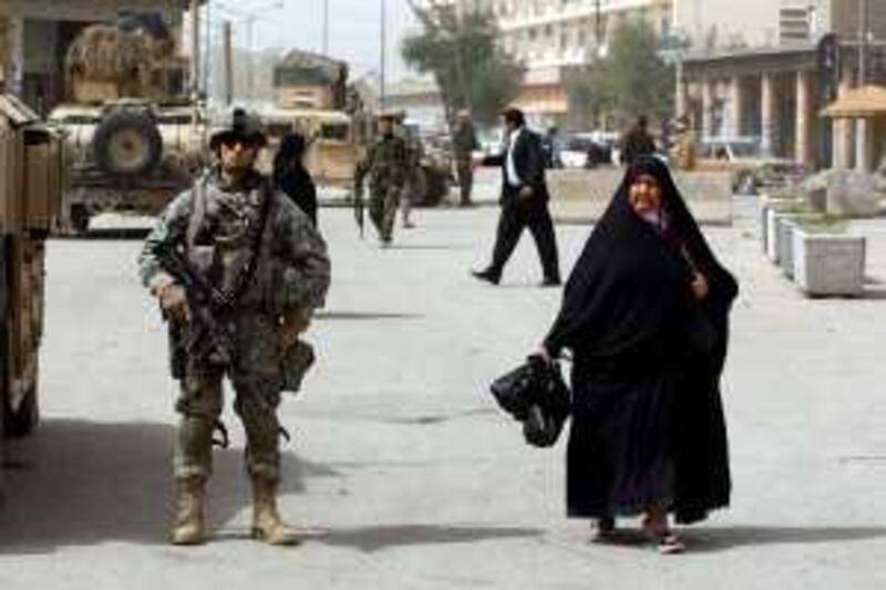 An Iraqi woman walks past a US soldier patrolling Baghdad's al-Fadel street on March 14, 2009. The White House has dismissed suggestions that two recent bloody attacks in Iraq were a reaction to President Barack Obama's decision to pull out most combat troops by August next year. White House spokesman Robert Gibbs said security challenges remained in Iraq, but said US agreements with the Baghdad government would not have been made if they were likely to plunge Iraq back into "danger." AFP PHOTO/ALI YUSSEF *** Local Caption ***  Nic347545.jpg