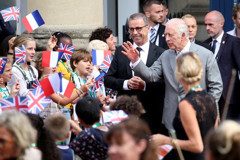 King Charles III waves to children as he is welcomed by Bordeaux Mayor Pierre Hurmic. Reuters