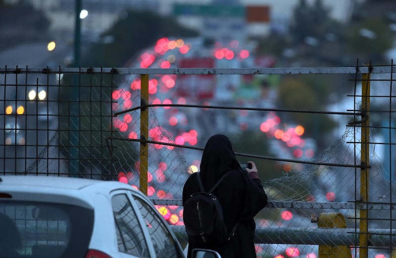 A woman takes pictures after protesters blocked roads using vehicles after the petrol price increase in Tehran.  EPA