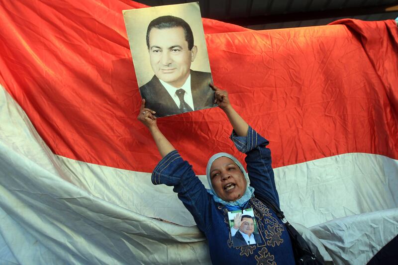 A supporter of ousted Egyptian President Hosni Mubarak holds his picture outside the police academy where Mubarak's trial is held on the outskirt of Cairo on August 3, 2011  .  TOPSHOTS    AFP PHOTO/KHALED DESOUKI
 *** Local Caption ***  543488-01-08.jpg