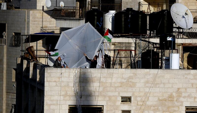 epa08362952 Palestinians fly a kite from their home roof over a neighborhood of the West Bank City of Nablus, 14 April 2020. Nablus was closed due to the current novel coronavirus emergency after the Palestinian National Authority (PA) has imposed a new 14-day period of home confinement for all Palestinians living in the West Bank amid the ongoing pandemic of the COVID-19 disease caused by the SARS-CoV-2 coronavirus.  EPA/ALAA BADARNEH