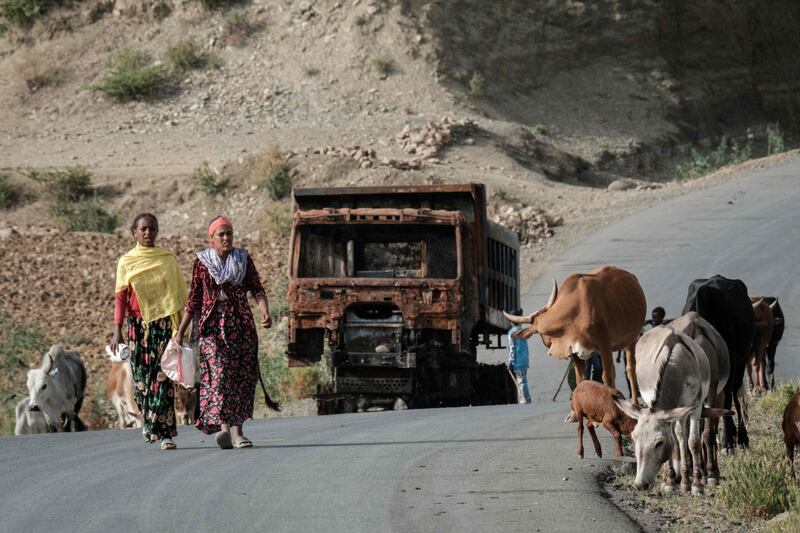 Women walk in front of a burnt lorry on the road near Dansa, south-west of Mekele, in the Tigray region on June 20. AFP