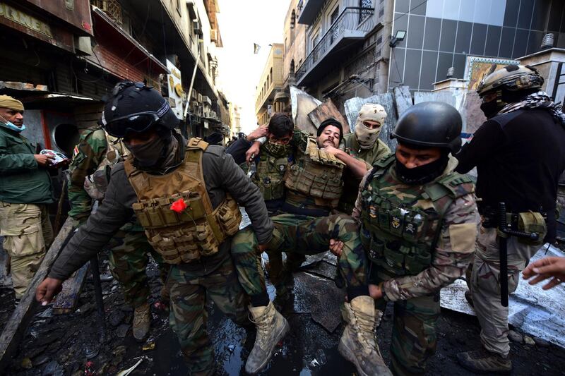 Iraqi security forces help an injured soldier during clashes on Rasheed Street. EPA