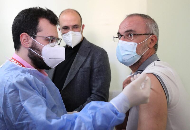 Lebanon's caretaker health minister Hamad Hassan (C) watches as a Lebanese teacher receives a Covid-19 AstraZeneca vaccine in Beirut on March 29, 2021. The country of over six million people has officially recorded more than 455,000 coronavirus cases and over 6,000 deaths. / AFP / ANWAR AMRO
