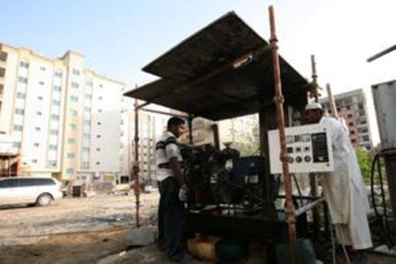 Workers operate the generator to supply electricity to a building in Ajman.