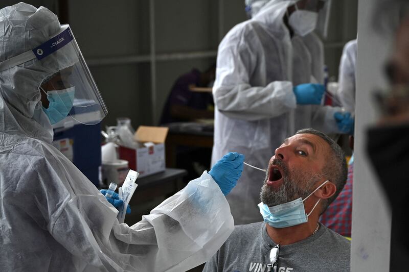 A health worker collects a swab sample from a passenger arriving on an international flight to test for the Covid-19 coronavirus at Chennai International Airport in Chennai, east India.