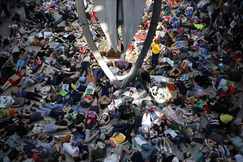 Extinction Rebellion climate change activists perform a mass "die in" under the blue whale in the foyer of the Natural History Museum in London.  AFP