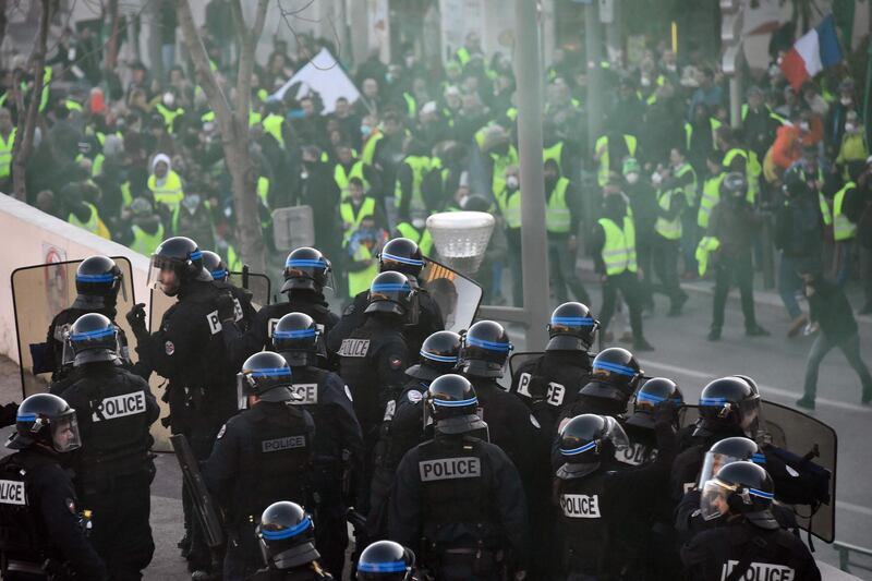 TOPSHOT - Protestors face riot police, on January 19, 2019 in Marseille, during a demonstration called by the yellow vests (gilets jaunes) movement in a row of nationwide protest for the tenth consecutive saturday against high cost of living, government tax reforms and for more "social and economic justice."  / AFP / CHRISTOPHE SIMON
