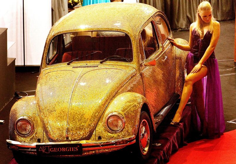 A model poses next to a 1968 Volkswagen Beetle covered in tiles made of a blend of 18 karat gold and glass at the annual Luxury Show in Bucharest, Romania. AP Photo