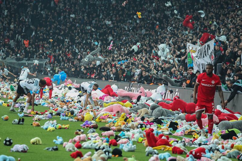 Players from Besiktas and Antalyaspor move toys to side of pitch after fans threw them down from stands. AP