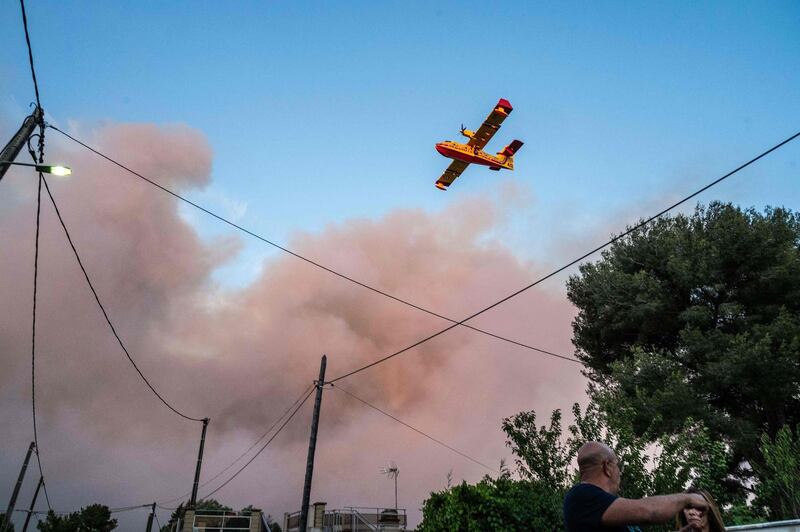 A French Securite Civile plane flies past a column of smoke, as wild fires broke out in La Couronne. AFP