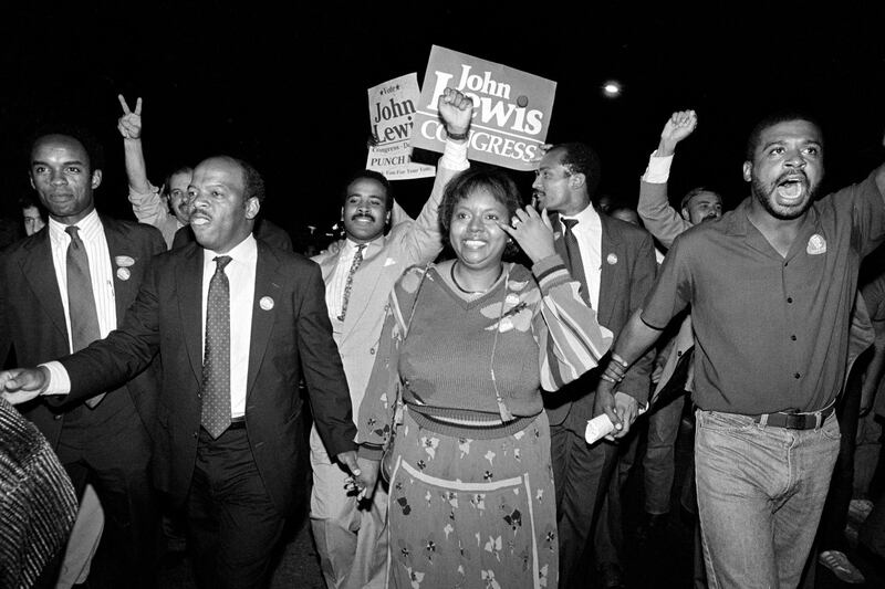 John Lewis, front left, and his wife, Lillian, holding hands, lead a march of supporters from his campaign headquarters to an Atlanta hotel for a victory party after he defeated Julian Bond in a runoff election for Georgia's 5th Congressional District seat in Atlanta, on September 3, 1986. AP Photo