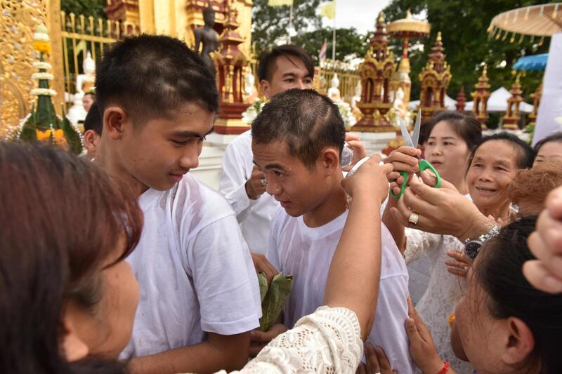 Family members cut the hair of Chantawong, centre, together with the rescued members of "Wild Boars" football team. AFP