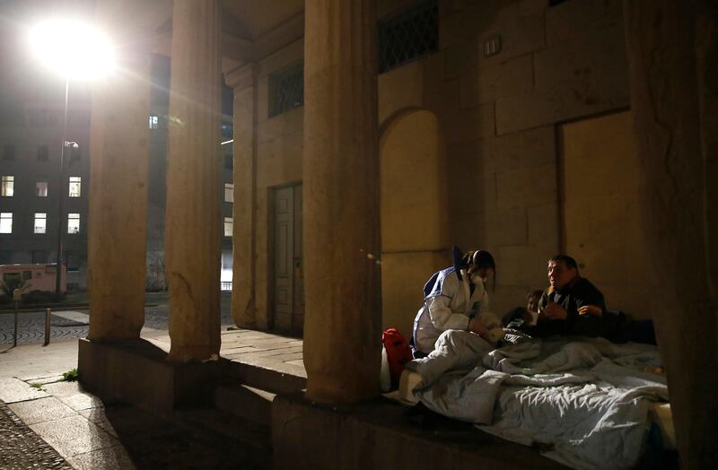 A volunteer nurse tends to a homeless person in Milan, Italy. AP Photo