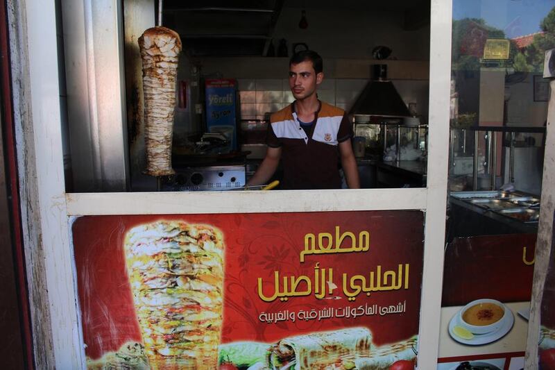 A worker tends to the shawarma spit at Orijinal Halep Lokantasi, a Syrian restaurant in Gaziantep. While Syrian-owned businesses must use Turkish in their names and on their main signage, smaller signs in Arabic, as seen here, are permitted. Josh Wood for The National.