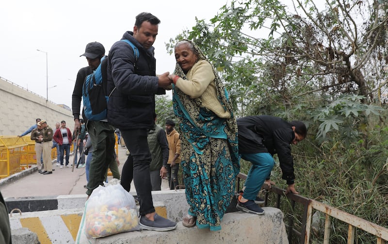 People cross the barricades placed by security personnel at the Delhi Ghazipur border. EPA