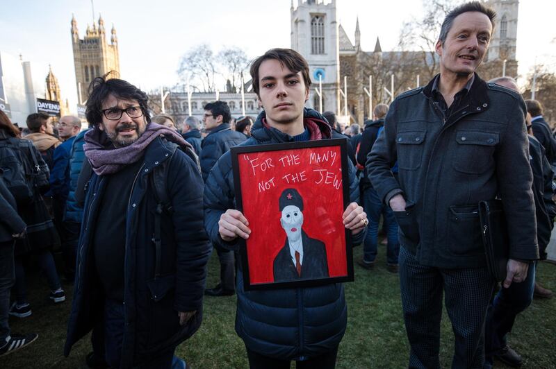 LONDON, ENGLAND - MARCH 26: A protester holds a framed image of Labour Leader Jeremy Corbyn and the words "For The Many Not The Jew" during a demonstration in Parliament Square against anti-Semitism in the Labour Party on March 26, 2018 in London, England. The Board of Deputies of British Jews and the Jewish Leadership Council have drawn up a letter accusing Labour Leader Jeremy Corbyn of failing to address anti-Semitism in his party. Mr Corbyn has today apologised to Jewish groups for "pockets of anti-Semitism" in Labour. (Photo by Jack Taylor/Getty Images)