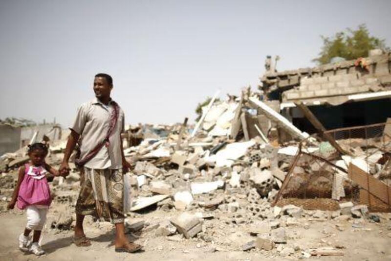 A man and his daughter displaced by fighting between the army and militants, survey a destroyed neighbourhood in the Yemeni city of Zinjibar, capital of Abyan province.