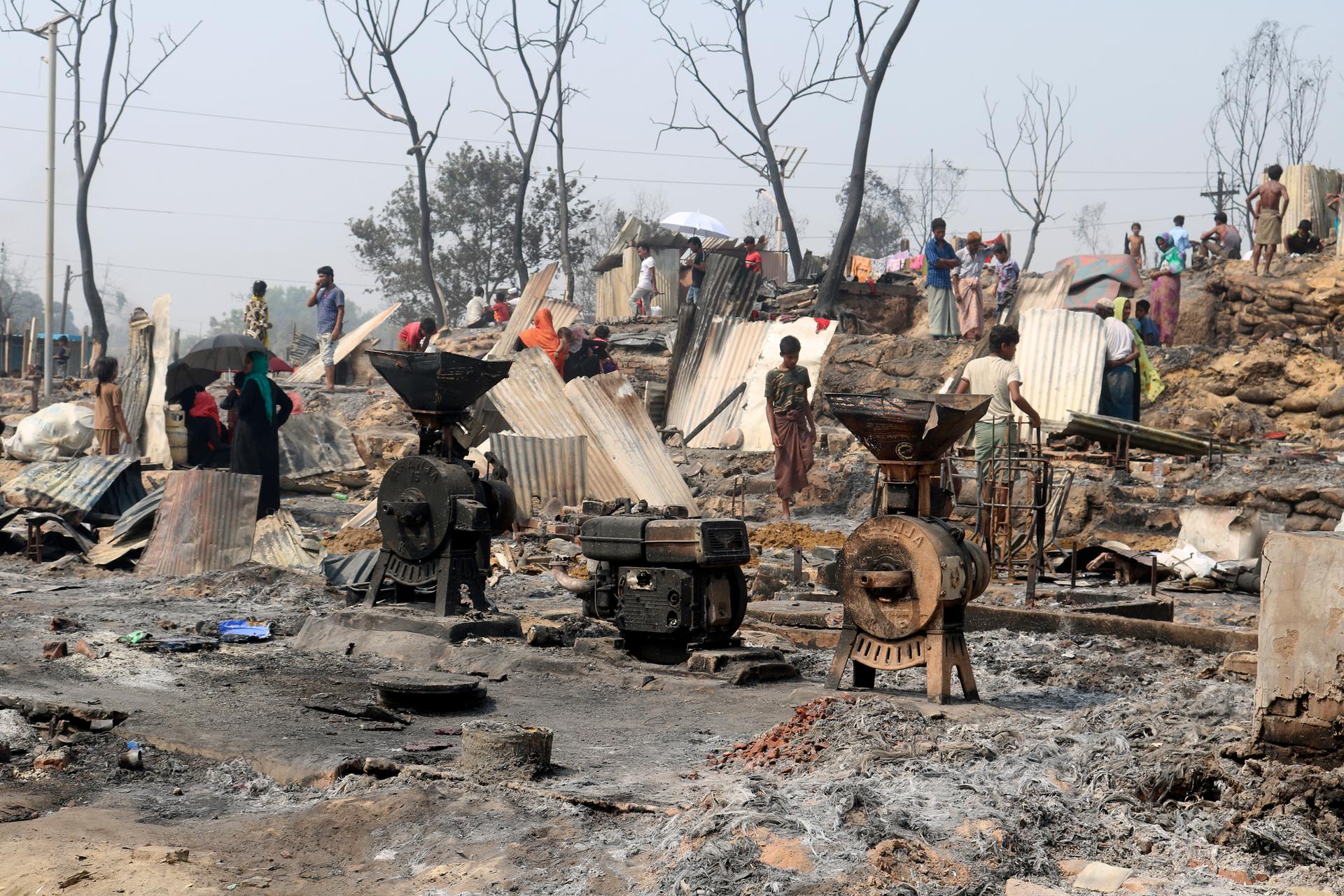 Rohingya refugees stand by remains of Monday's fire at a refugee camp in Balukhali, southern Bangladesh. AP Photo