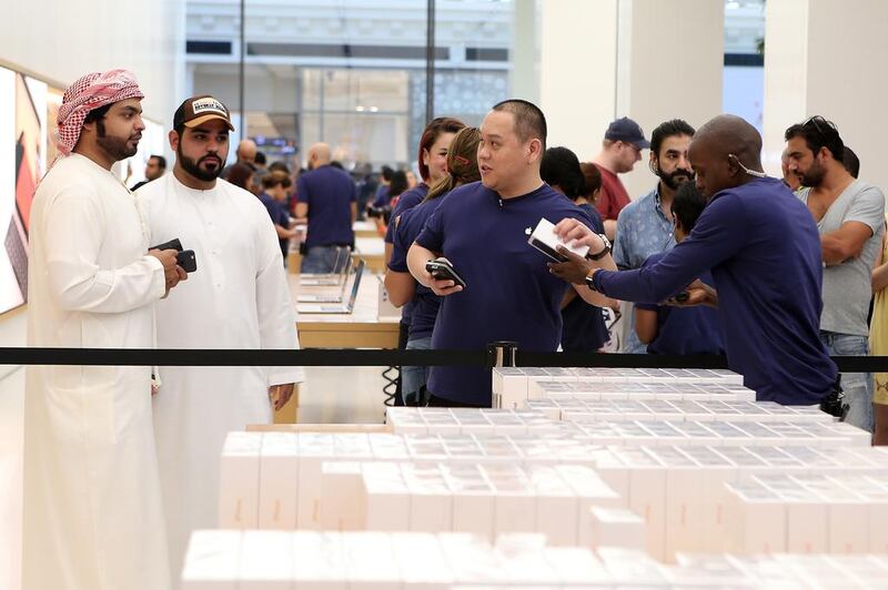 Customers buy the iPhone 7 at the Apple store in Dubai's Mall of the Emirates. The company shipped a record number of smartphones in the fourth quarter despite a critical panning of the phone. Pawan Singh / The National