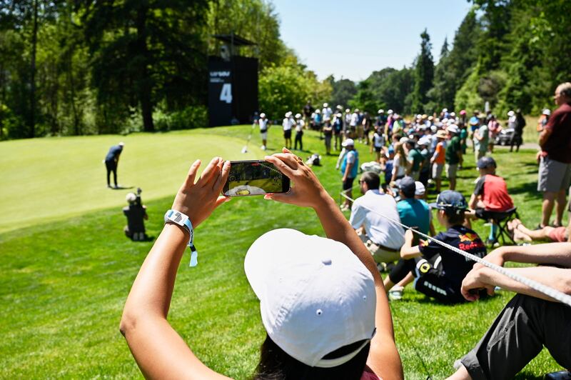 Golf fans take pictures of Brooks Koepka of the US on the fourth hole. EPA
