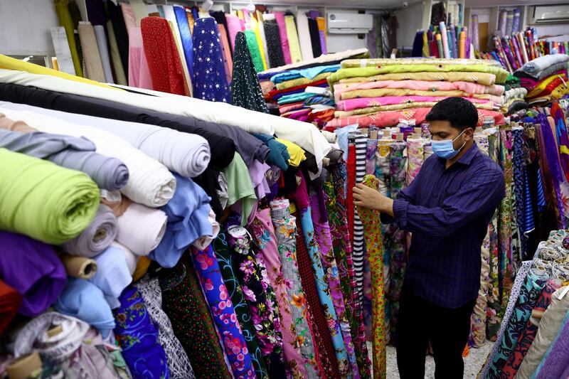SHARJAH, UNITED ARAB EMIRATES - JULY 29: A man arranges fabric at a store ahead of Eid Al-Adha on July 29, 2020 in Sharjah, United Arab Emirates. Eid al-Adha is the second of two Islamic holidays celebrated by Muslims worldwide each year, the other being Eid al-Fitr. Celebrations are subdued in many places this year due to covid-19 restrictions on travel and gatherings. (Photo by Francois Nel/Getty Images)