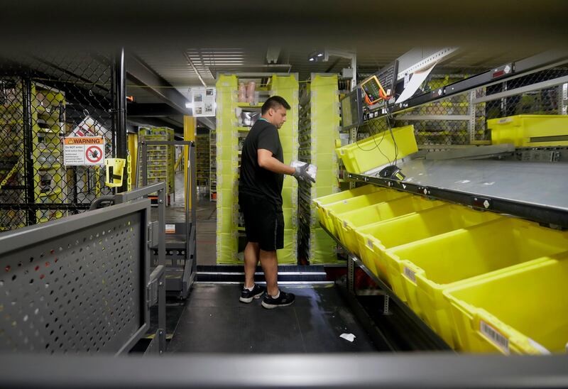 In this Tuesday, Aug. 1, 2017, photo, an Amazon employee sorts items brought to him by robotic shelves at the Amazon Fulfillment center in Robbinsville Township, N.J. Amazon is holding a giant job fair Wednesday, Aug. 2, and plans to make thousands of job offers on the spot at nearly a dozen U.S. warehouses. (AP Photo/Julio Cortez)