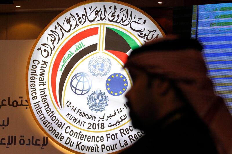 A Kuwaiti official stands in front of an illuminated sign for a conference on Iraq being held in Kuwait City, Kuwait, Monday, Feb. 12, 2018. Kuwait this week is hosting a series of conferences on rebuilding Iraq after the onslaught of the Islamic State group. (AP Photo/Jon Gambrell)