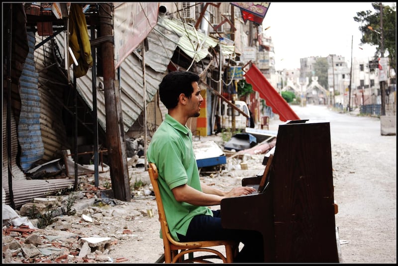 The famous image of Aeham Ahmad playing a piano amid the destruction of war in 2014 was taken by Niraz Saied. The photographer was arrested by the Syrian Army and died in jail last year. Courtesy Niraz Saied