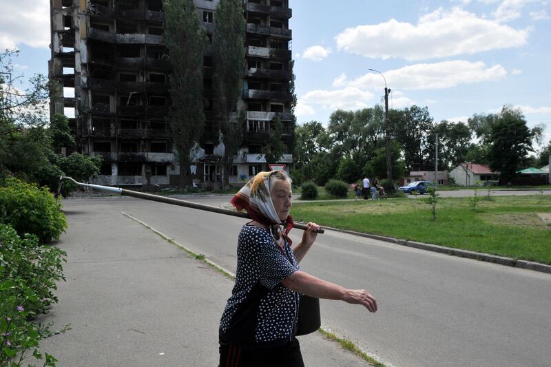 A woman walks by a destroyed apartment building in the town of Borodyanka. AFP