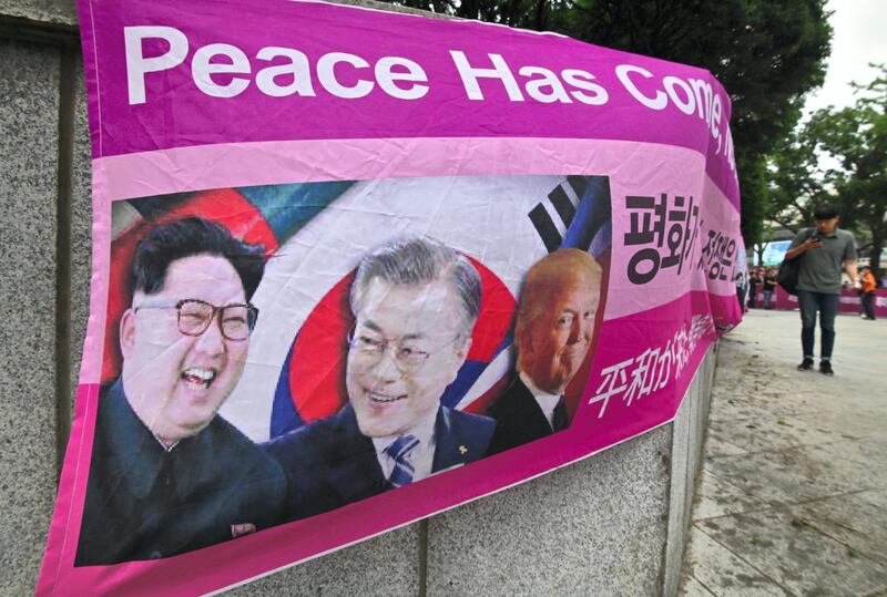 A man walks past a banner showing pictures of (L-R) North Korean leader Kim Jong Un, South Korean President Moon Jae-in and US President Donald Trump, during a protest urging Trump to carry out the North Korea-US joint agreement signed in Singapore, near the US embassy in Seoul on June 29, 2019. - Trump is to arrive in the South Korean capital on June 29 to hold talks with South Korean President Moon Jae-in, after offering to meet with North Korean leader Kim Jong Un at the demilitarised zone between the two Koreas in a surprise tweet. (Photo by Jung Yeon-je / AFP)