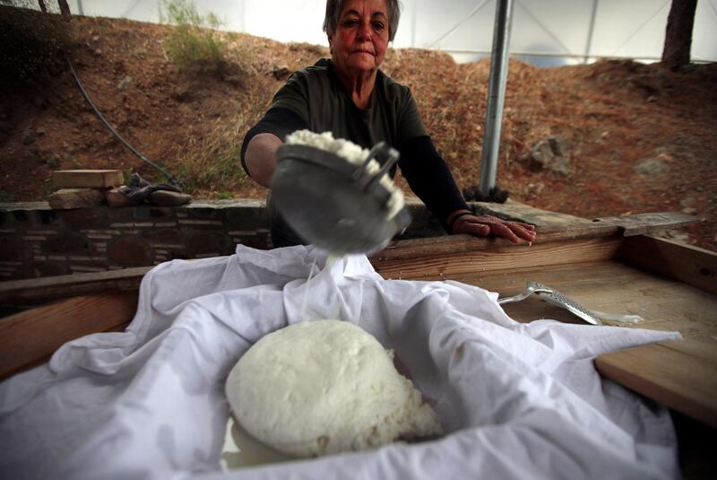 FILE - In this Wednesday Dec. 11, 2019 file photo, Aphrodite Philippou, 73, takes out cheese from a saucepan as she makes Cyprus' halloumi cheese at a farm in Kampia village near Nicosia, Cyprus. Cyprusâ€™ agriculture minister on Tuesday, March 30, 2021 said the European Unionâ€™s decision to recognize halloumi as a Cypriot traditional product will shield the countryâ€™s top food export from an increasing number of foreign producers using the cheeseâ€™s name to muscle into a 224 million euro ($267 million) market. (AP Photo/Petros Karadjias, file)