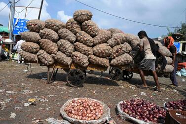 Workers push a handcart loaded with gunny bags filled with onions at a wholesale vegetable market in New Delhi, India. AFP