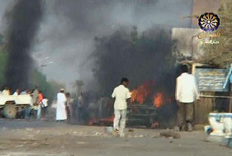 In an image grab taken from Sudan TV on May 11, 2008, black smoke billows from burning cars as Sudanese people walk along the streets in Khartoum's twin city Omdurman, following fighting between Darfurian rebels and Sudanese government forces. Sudan today severed diplomatic ties with Chad, accusing Ndjamena of backing a first Darfur rebel assault on Khartoum, and slapped a multi-million dollar price on the head of the alleged mastermind. AFP PHOTO/DSK   --RESTRICTED TO EDITORIAL USE-- (Photo by Sudan TV / AFP)