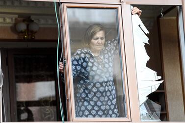 A woman removes broken glass from a window in an apartment building that was damaged by recent shelling in the breakaway Nagorno-Karabakh region's main city of Stepanakert. AFP  