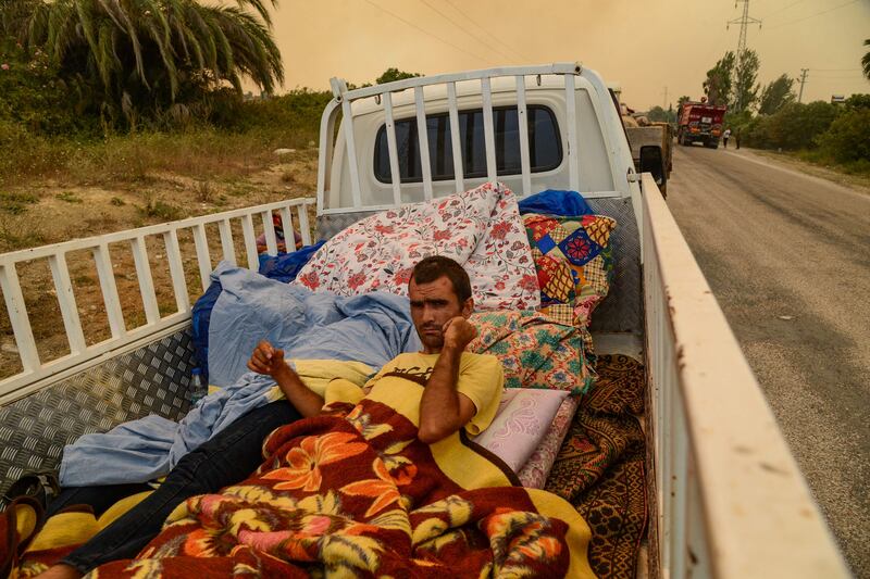 A man lies on a mattress on the back of a truck as residents leave the area during a bushfire near the town of Manavgat.