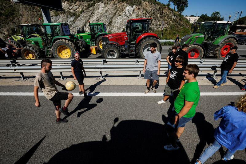 People play with a ball during a blockage of a motorway in Le Perthus, Spain, near the border with France, as farmers demand better conditions before European elections. Reuters
