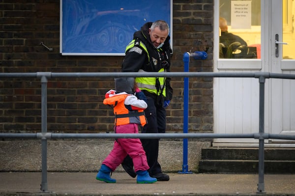 An officer assists a young girl as she leaves a coast guard boat in Dover, south-east England. Getty Images