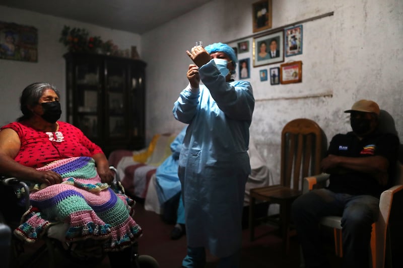 A healthcare worker prepares to give a woman a Covid-19 vaccine dose in Lima, Peru. Reuters