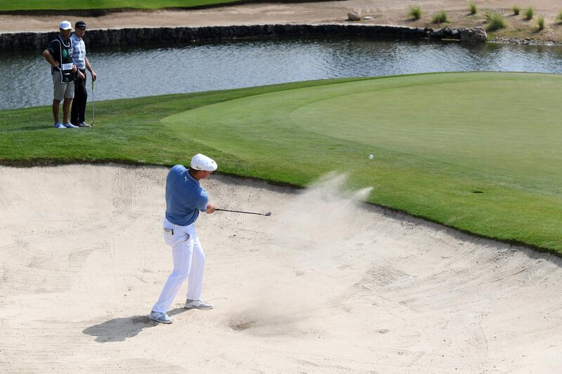Bryson DeChambeau plays from a green side bunker, watched by playing partner Justin Rose. Getty