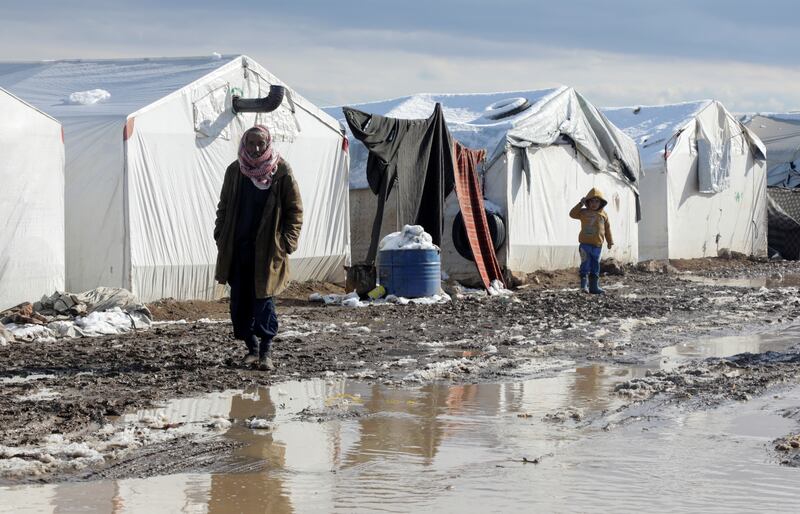 A man walks through mud near tents at a camp for internally displaced people in the northern Aleppo countryside. Reuters