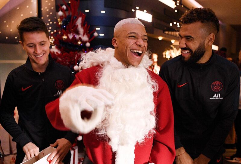 Kylian MBappe dressed as Santa Claus with Paris Saint-Germain's Spanish midfielder Ander Herrera and Cameroon forward Eric Maxim Choupo-Moting.  They were giving gifts to children from the foundation of PSG after the match against Amiens at the Parc des Princes. AFP